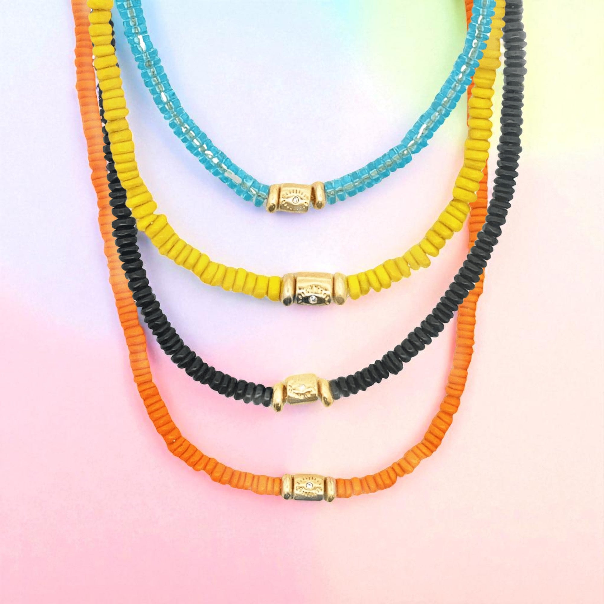 Three colorful beaded necklaces with gold clasp on a gradient background