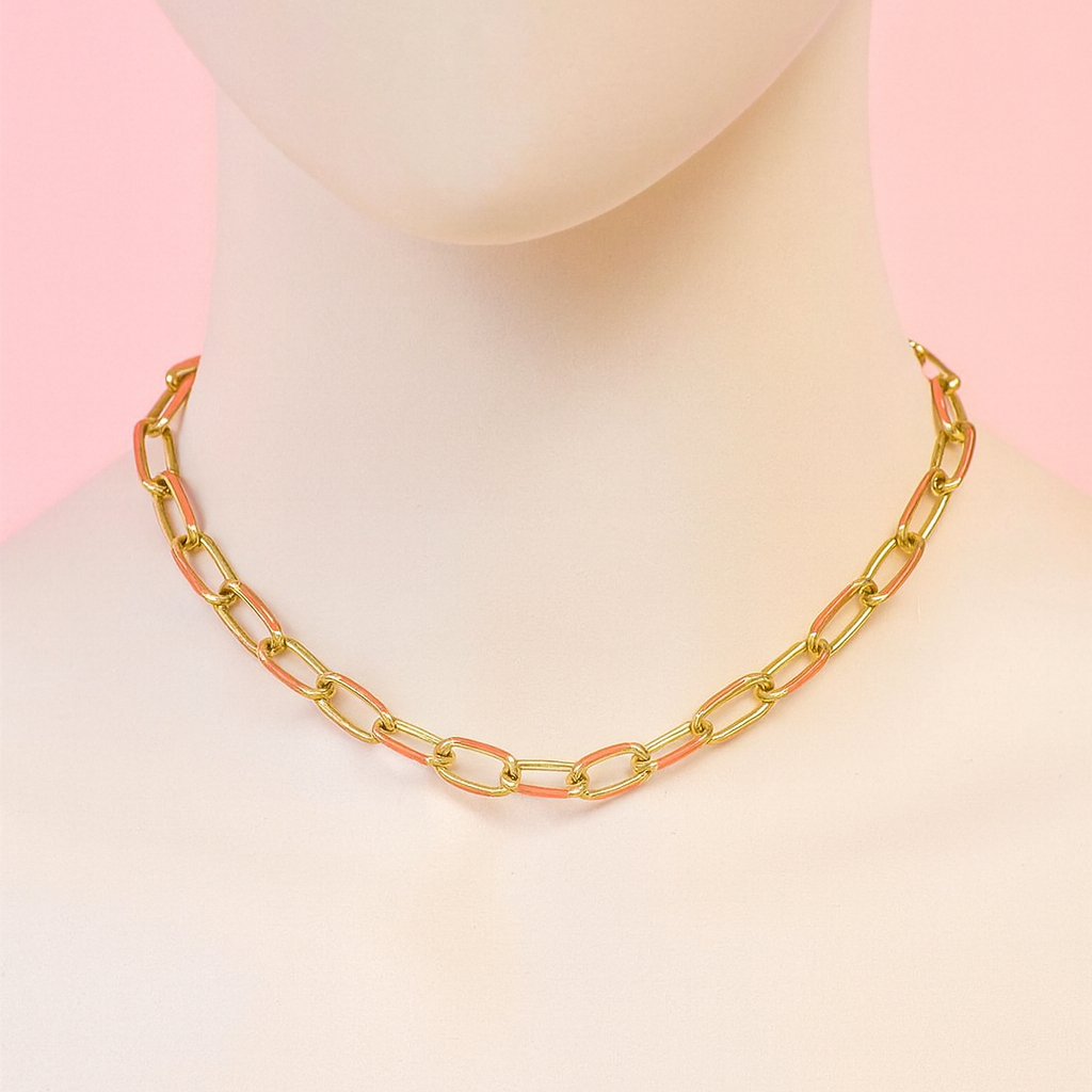 Gold chain necklace on a mannequin against a pink background