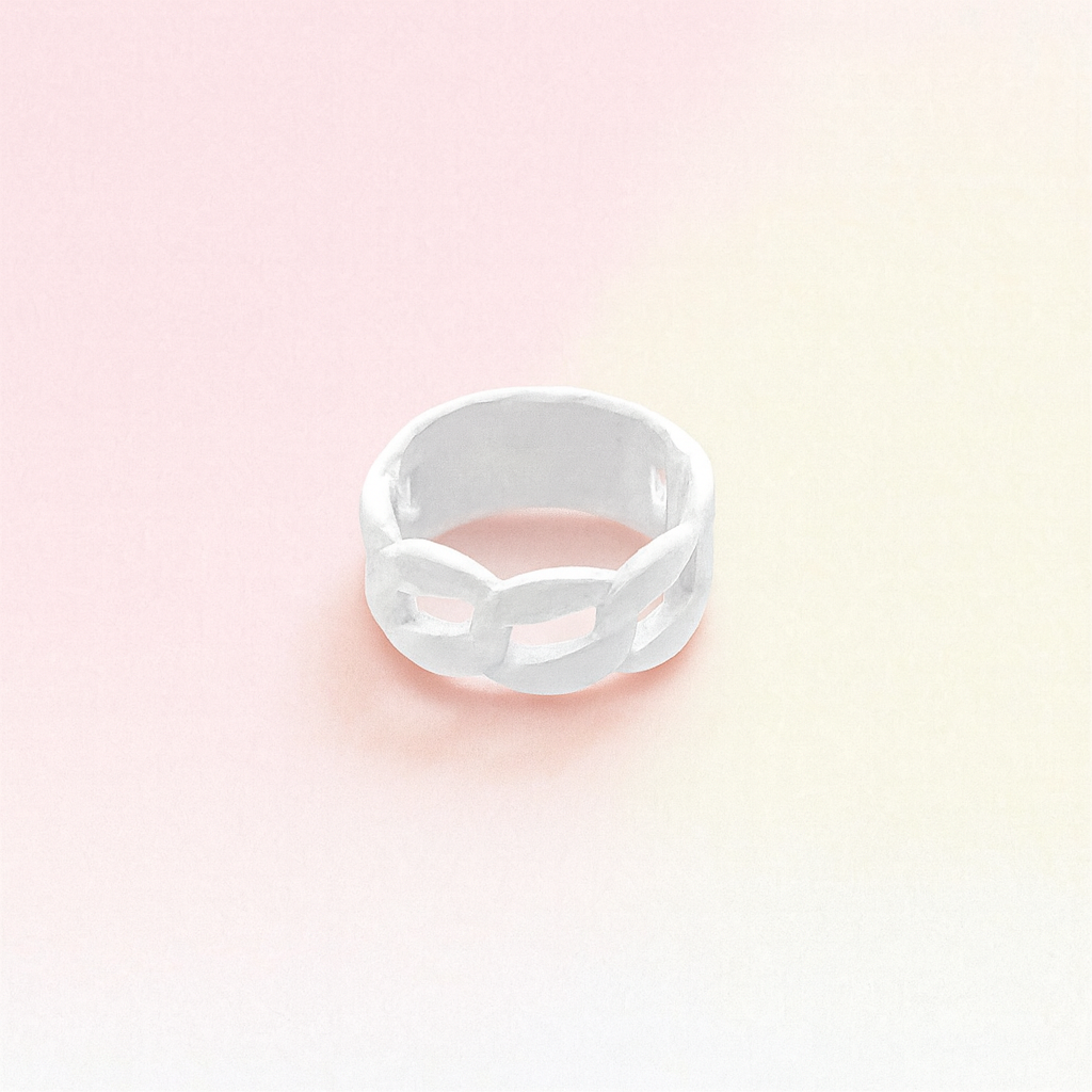 Silver ring on a pastel pink and beige gradient background
