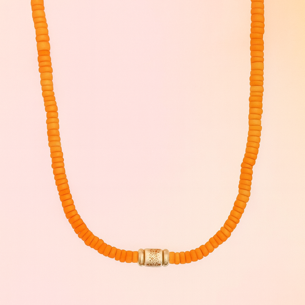 Orange beaded necklace with a gold clasp on a pink background