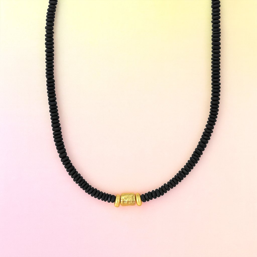 Black beaded necklace with a gold clasp on a gradient background