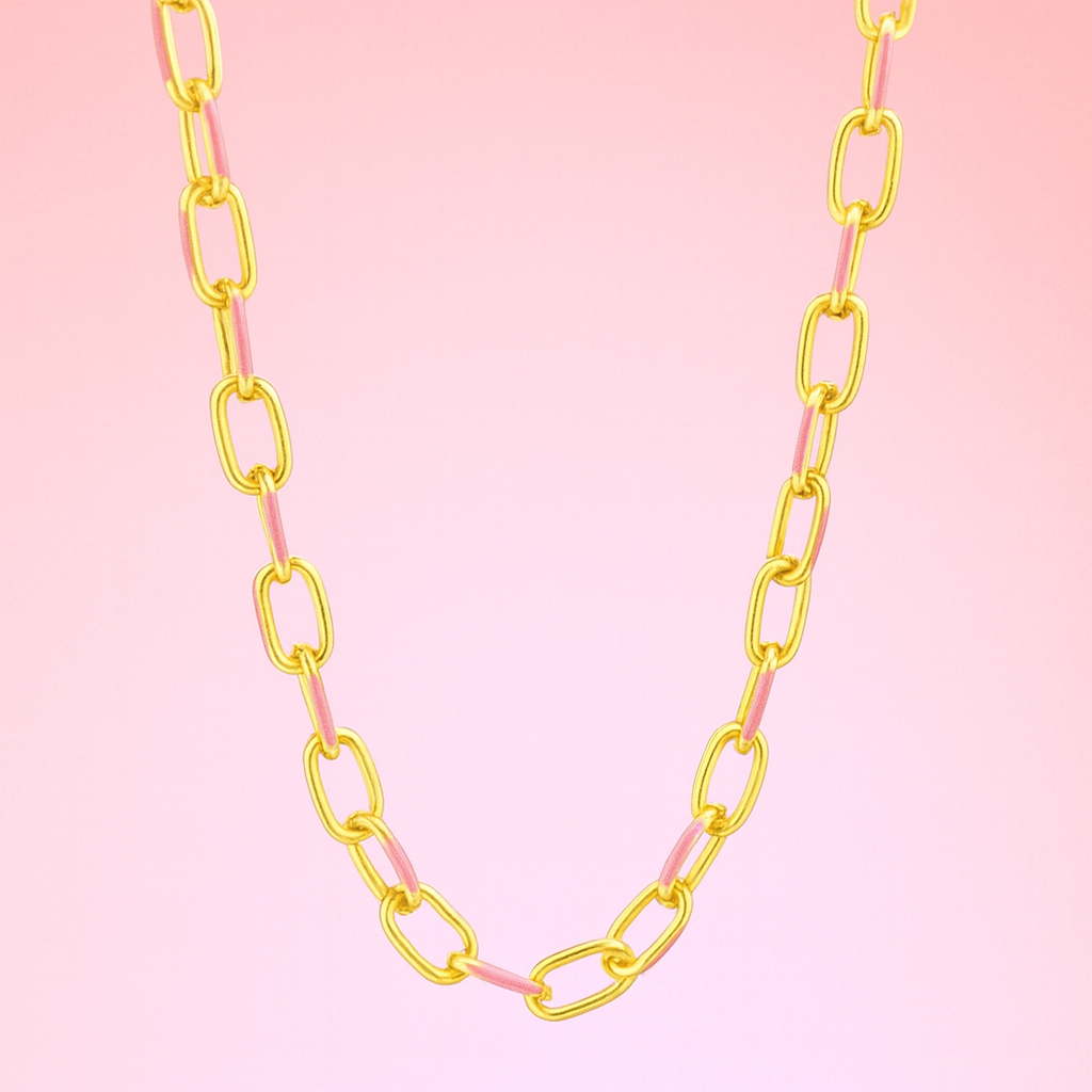 Gold chain necklace on a pink background