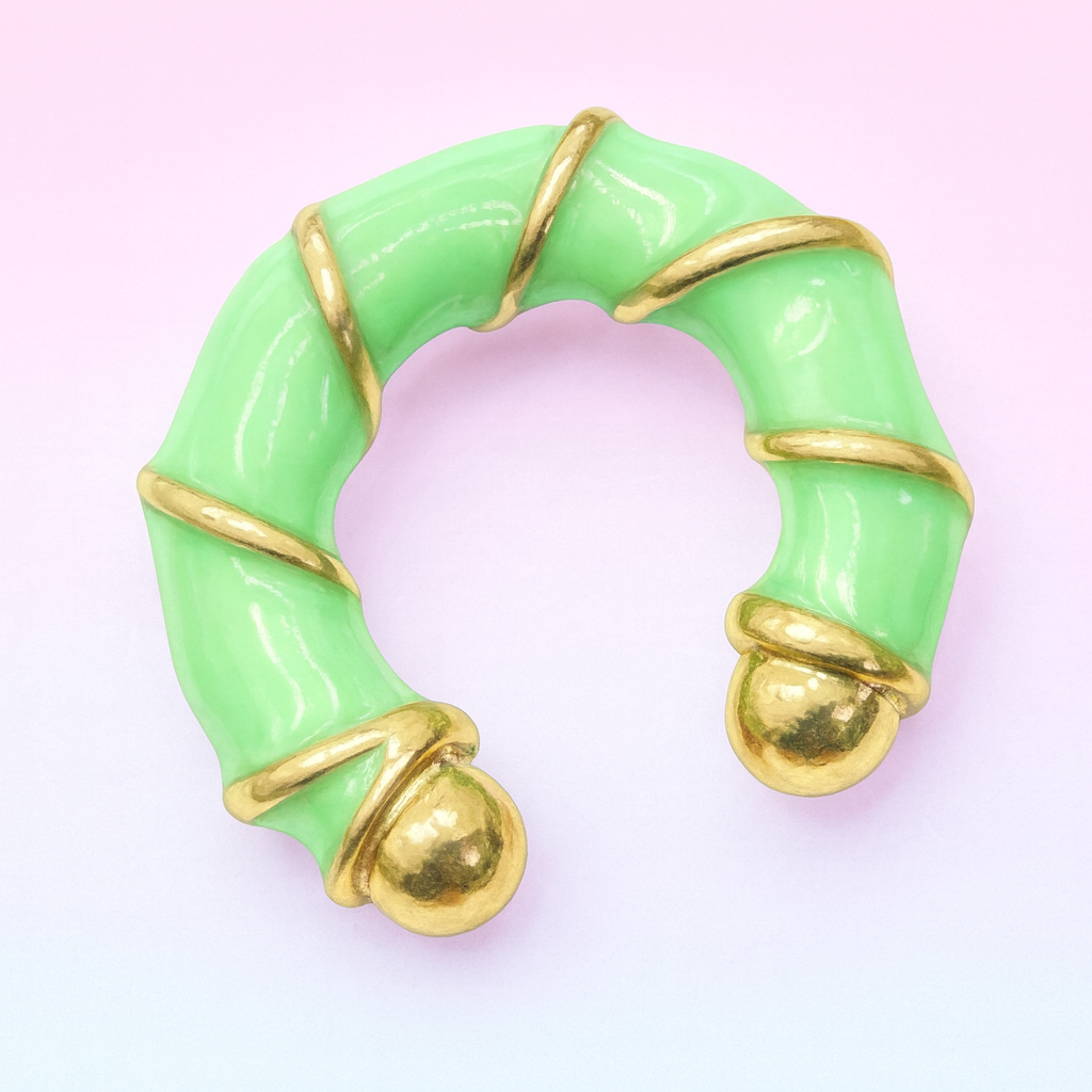 Green ring with gold accents on a pink background