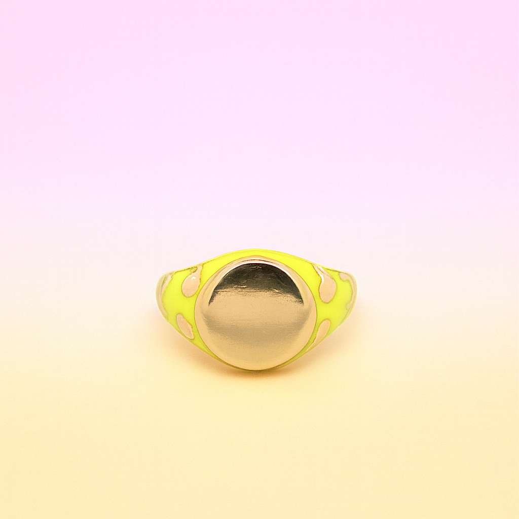 Gold ring with a yellow polka dot band on a gradient background