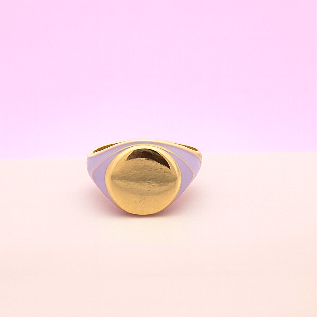 Gold ring with purple band on a gradient pink and purple background