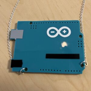 photography of laser-cut acrylic necklace of Arduino microcontroller