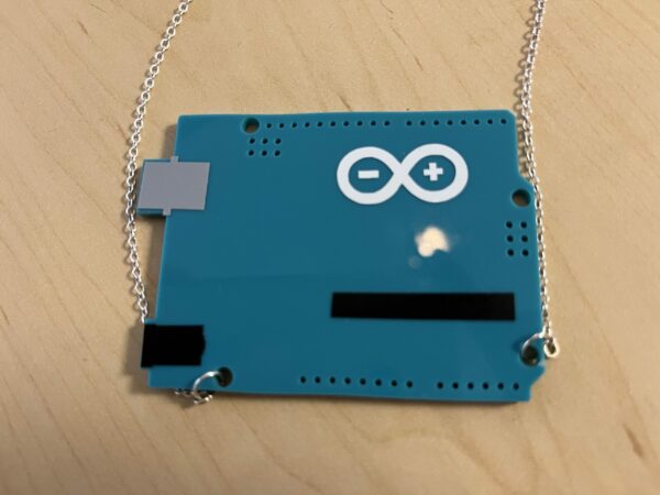 photography of laser-cut acrylic necklace of Arduino microcontroller